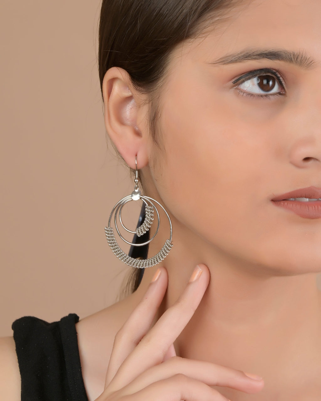 Close-up of a woman wearing a silver earring with a neutral background